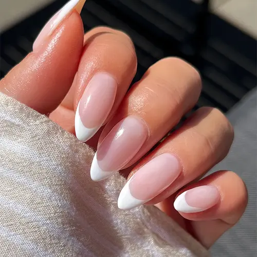 En bild på en kvinnohand med målade vita toppar nagellack